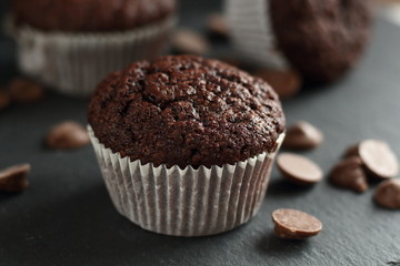 Chocolate homemade cupcakes muffins on a black background with chocolate drops in the background. Bakery style. Dark food photo
