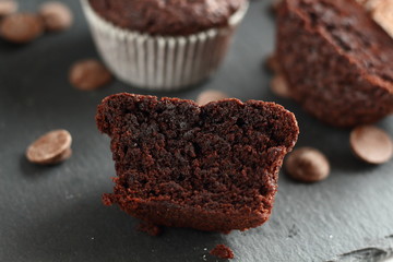 Chocolate homemade cupcakes muffins on a black background with chocolate drops in the background. Bakery style. Dark food photo