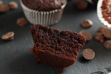 Chocolate homemade cupcakes muffins on a black background with chocolate drops in the background. Bakery style. Dark food photo