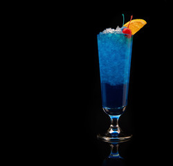 Tropical blue curacao cocktail garnished with a fresh orange slice and cherries on a black background