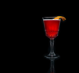 Glass of cosmopolitan cocktail decorated with orange on black background.