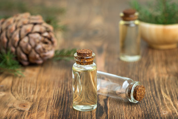 Cedar essential oil in a glass bottle. Soft focus. Wooden background.