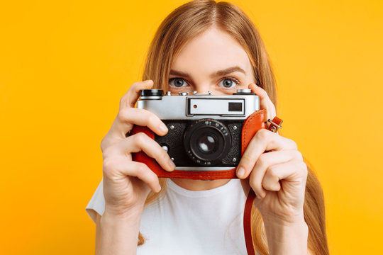beautiful girl with a camera in her hands, on a yellow background