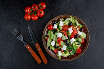 Greek salad with olives and feta on black background. Top view, flat lay
