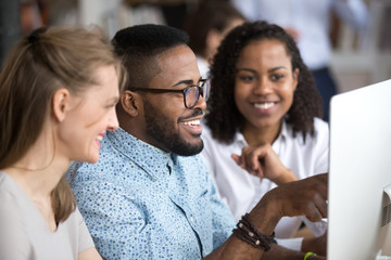 Smiling african team leader explaining computer task to employees group