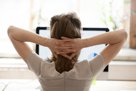 Rear View At Woman Resting From Computer Hands Behind Head