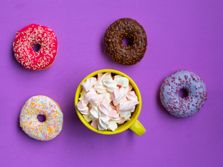 mix donuts with cup of marshmallow on purple background