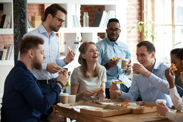 Happy diverse team people talking laughing eating pizza in office