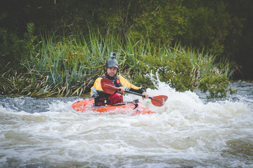 Fototapeta na wymiar Close up image of a white water kayak paddler riding white water on a mountain river