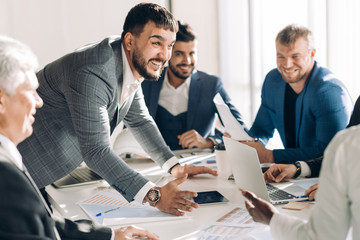 Emotionally excited multiracial businessmen discussing business documents, vivid real emotions and...