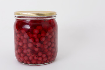 Red currant in a glass jar on a white background.