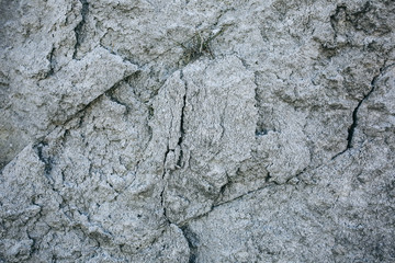 Chapped desert ground texture. White grey sand with stone background.