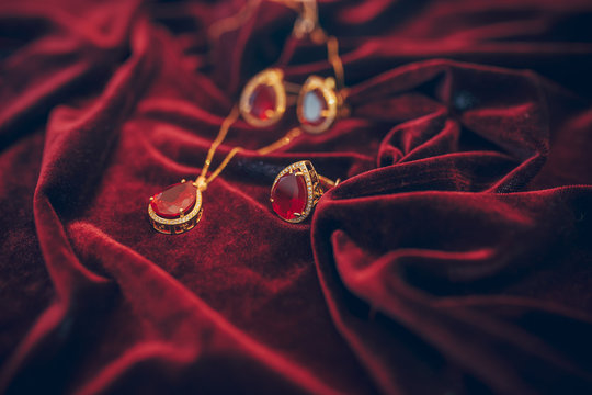 Golden Jewelry With Gem On The Red Velvet Background