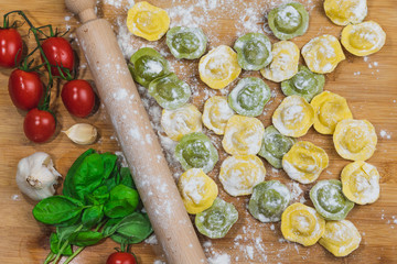 Fototapeta na wymiar Homemade fresh Italian ravioli pasta on wood table with flour, basil,tomatoes,background,top view.