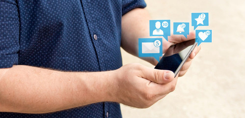 Young man holding smartphone with icons of notifications from social media. Social media concept. Chat.