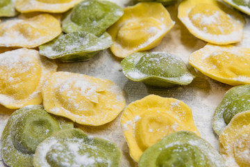 Homemade fresh Italian ravioli pasta on white wood table  with flour close-up.