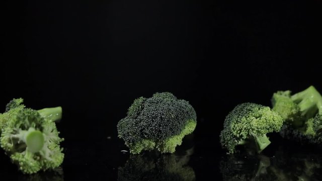 Close-up of raw broccoli is falling down on black background