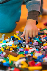 Close up of colorful plastic bricks on the floor. Early learning. Children's plastic constructor on the floor. Children's hands play a little constructor. vertical photo.