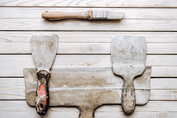 Kit of putty knives. Spatulas with the remaining mortar. Gastarbeiter or guest worker concept....