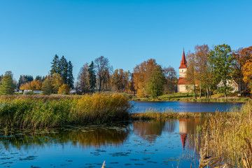 Fototapeta na wymiar Araisi Lutheran Church standing on the calm lake shore in sunny autumn day. Ancient church reflecting in the calm blue smooth surface of the lake.