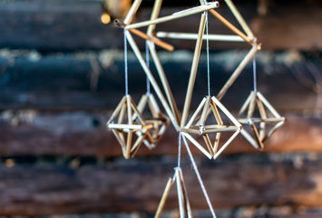 Latvian Puzurs hanging in the dark log hut. Puzurs is traditional Latvian room decoration made of reeds or straws. It is solstice symbol similar to Finnish Himmeli and Lithuanian Siaudinis Sodas.