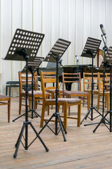 Empty seats and some instruments in music hall awaiting orchestra to come on the stage. black music stand on stage.