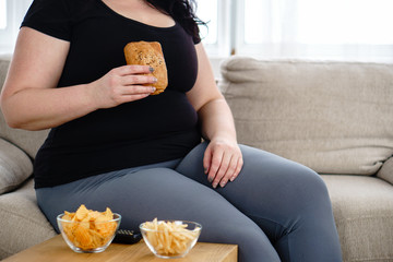 lack of physical activity, imbalanced nutrition, laziness, homebody. lonely fat woman watching...