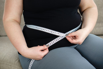 weight loss, overweight, plus size, diet. fat woman measures her waist with measuring tape