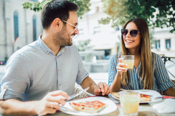 Couple eating pizza snack outdoors.They are sharing pizza and eating.