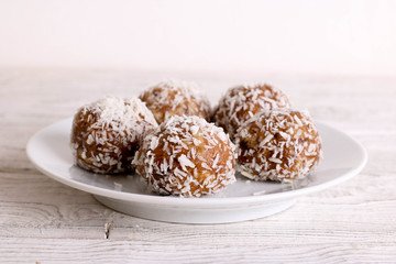 Homemade date candies covered with chocolate and shredded coconut