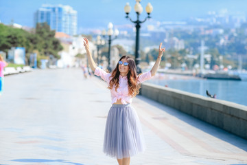 Girl walking along the seafront in dress in hot summer day