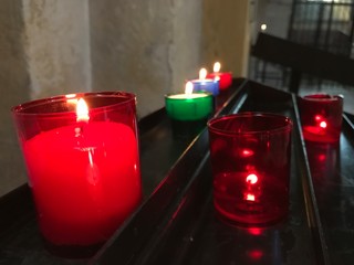Close-up of red, green and blue lighting candles in pedestal of church