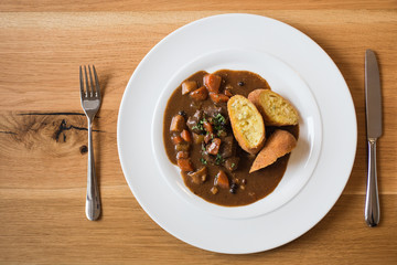 top view of delicious venison meal with croquettes on white plate and wooden table