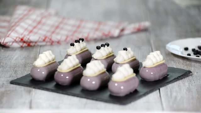 Confectioner decorates mousse cake with a blueberries Production of glazed desserts.