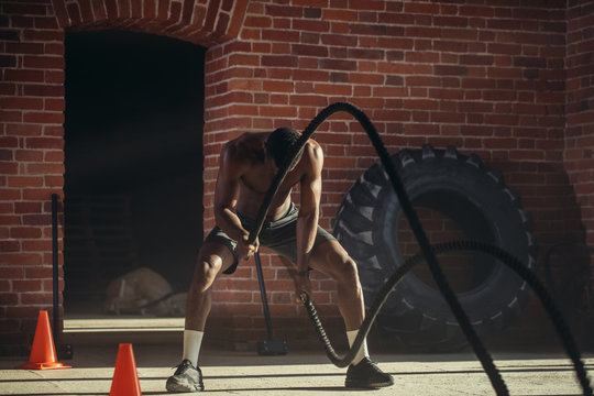 Hard work of Crossfit instructor of African ethnicity proves that training ropes are a very dynamic workout that accelerates athlete's pulse while strengthening his body.