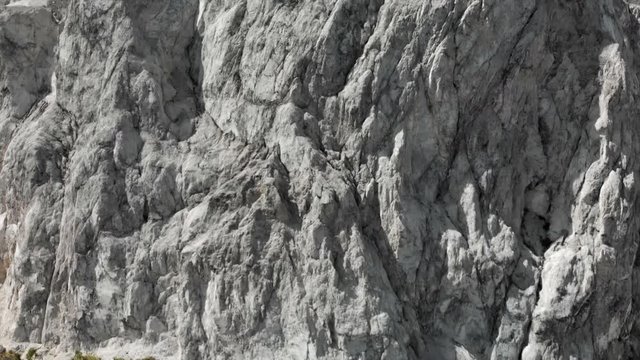 Aerial View Panning Up a White Rocky Textured Cliff