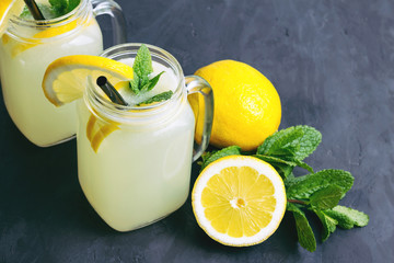 Refreshing lemonade drink with lemon slice and mint in the jar on dark background