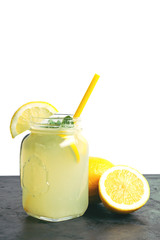Refreshing lemonade drink with lemon slice and mint in the jar on dark table and white background