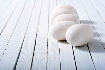 white painted wooden eggs on bright wood table background