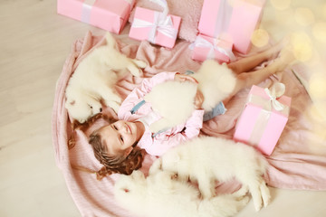 Little girl with white puppies and gift boxes