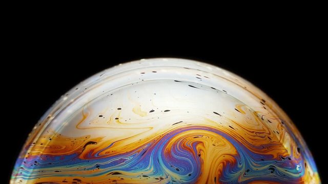 fascinating and magical movement of bright rainbow-colored neon streaks on the surface of a soap bubble as a result of diffraction and interference of light through a soap film