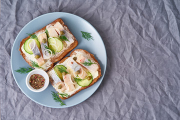 Herring smorrebrod - traditional Danish sandwiches. Black rye bread with herring on dark gray background, top view, copy space