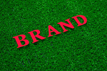 brand on artificial green grass background, red, green.