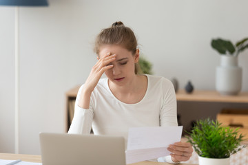 Sad young woman reading bad news in paper letter
