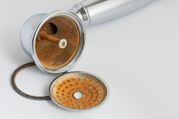 Broken rust-eaten shower head with limescale and rust stains on it
