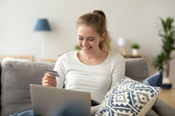 Happy young woman using laptop buying online with credit card