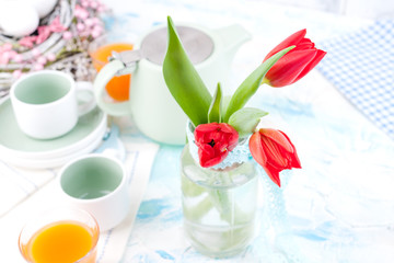 Bouquet of fresh red tulips in a vase on a white table. Spring Easter breakfast with flowers and free space for text.