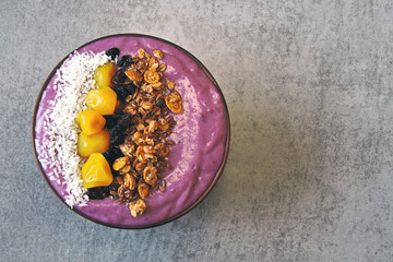 Bright colorful acai bowl with granola and dried fruit.