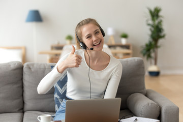 Smiling woman wearing headset showing thumbs up looking at camera