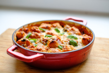 Homemade gnocchi baked in tomato sauce with spinach, toasted cheese on and fresh basil on top.